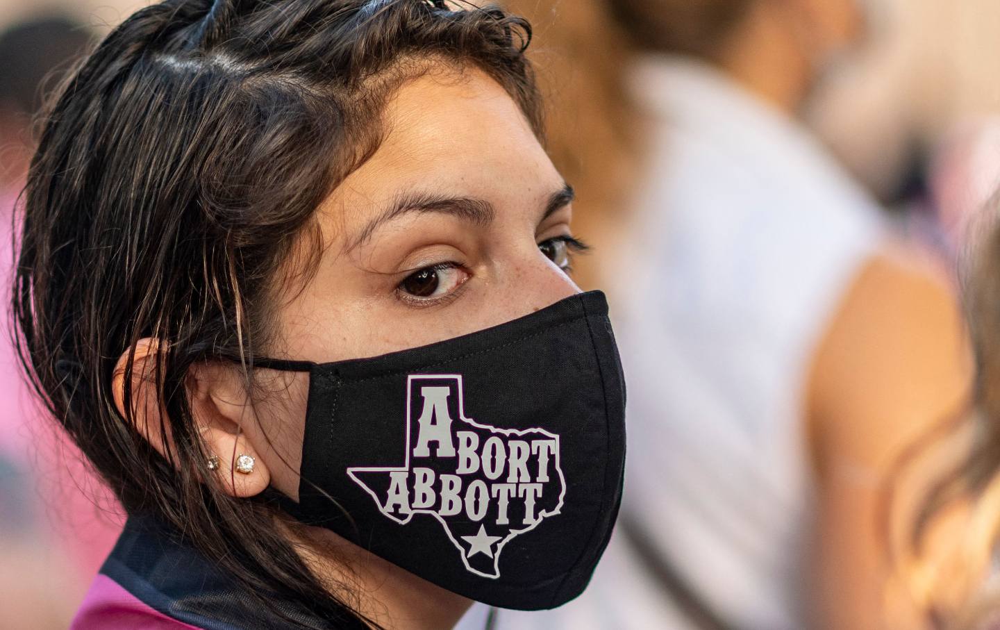Woman wearing "Abort Abbott" mask.