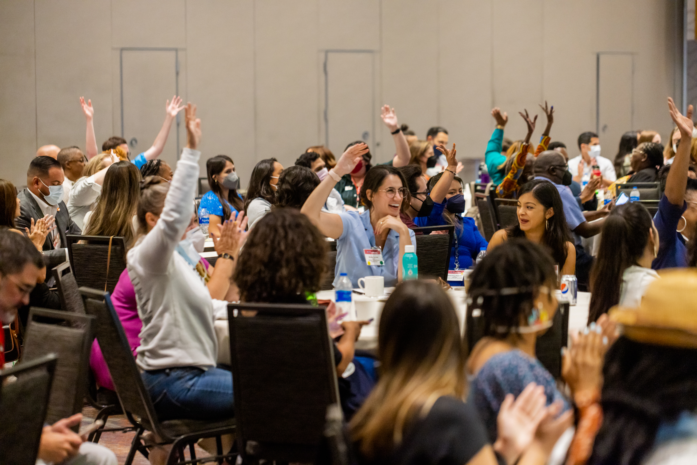 Local elected officials and partners raising their hands at a Local Progress convening.