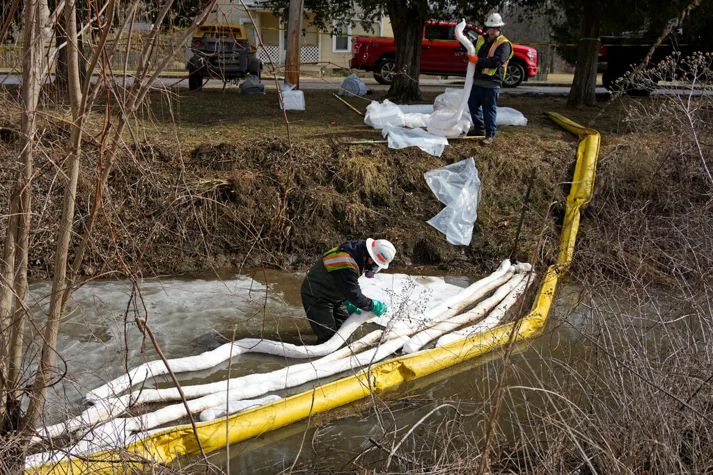 photo of environmental workers cleaning up the site of the train derailment in East Palestine