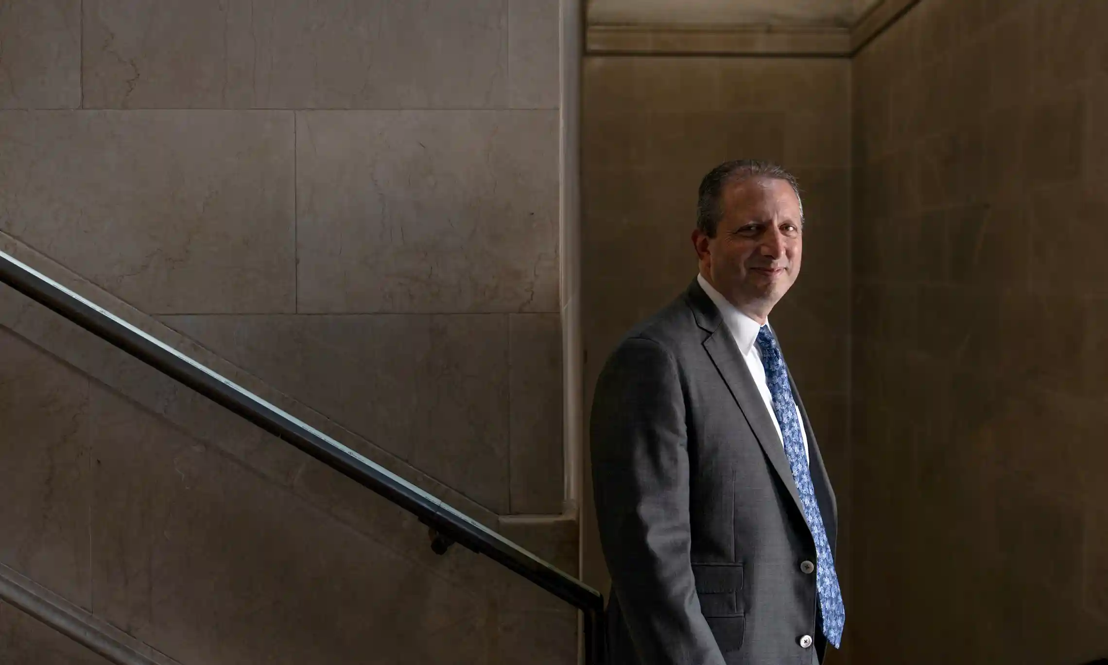 Photo of Brad Lander standing at the bottom of a staircase by Maria Spann/The Guardian.
