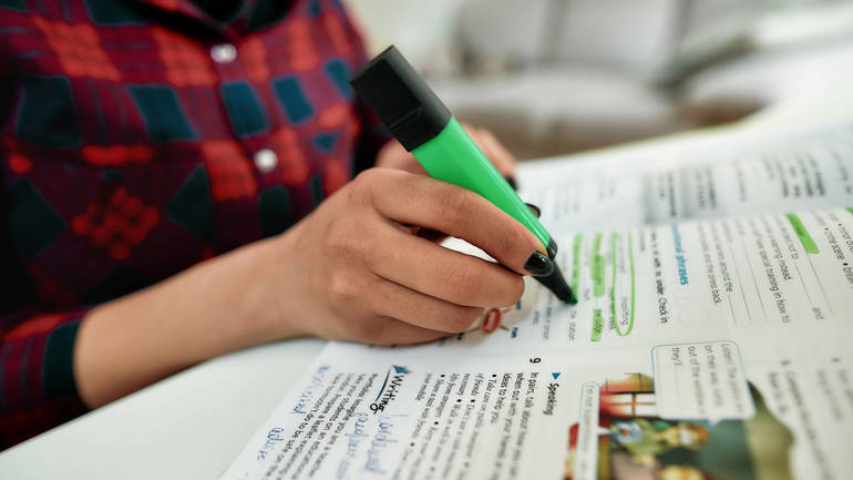 Close-up image of a person's hand highlighting text.