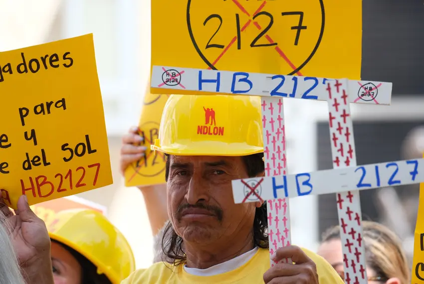 Members of the Fe Y Justice Worker Center hold signs to protest House Bill 2127, dubbed the "Death Star bill," during a press conference at Houston’s City Hall on July 14. Credit: Douglas Sweet Jr. for The Texas Tribune