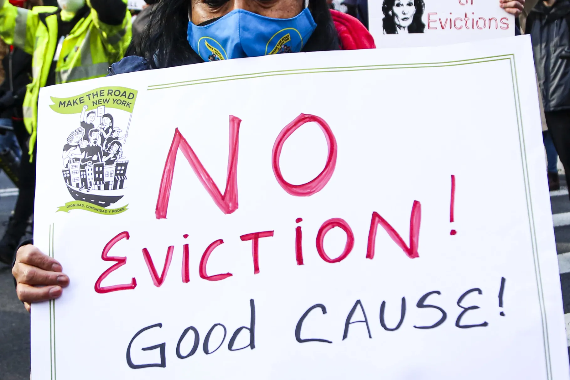 A picture of a woman in a mask holding a sign
