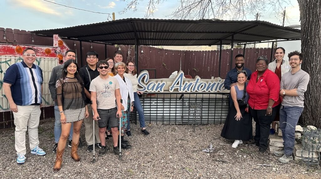 Photo of LPTX members, parters, and potential new members standing in front of a sign that says "San Antonio" at the 2024 TX PGA.
