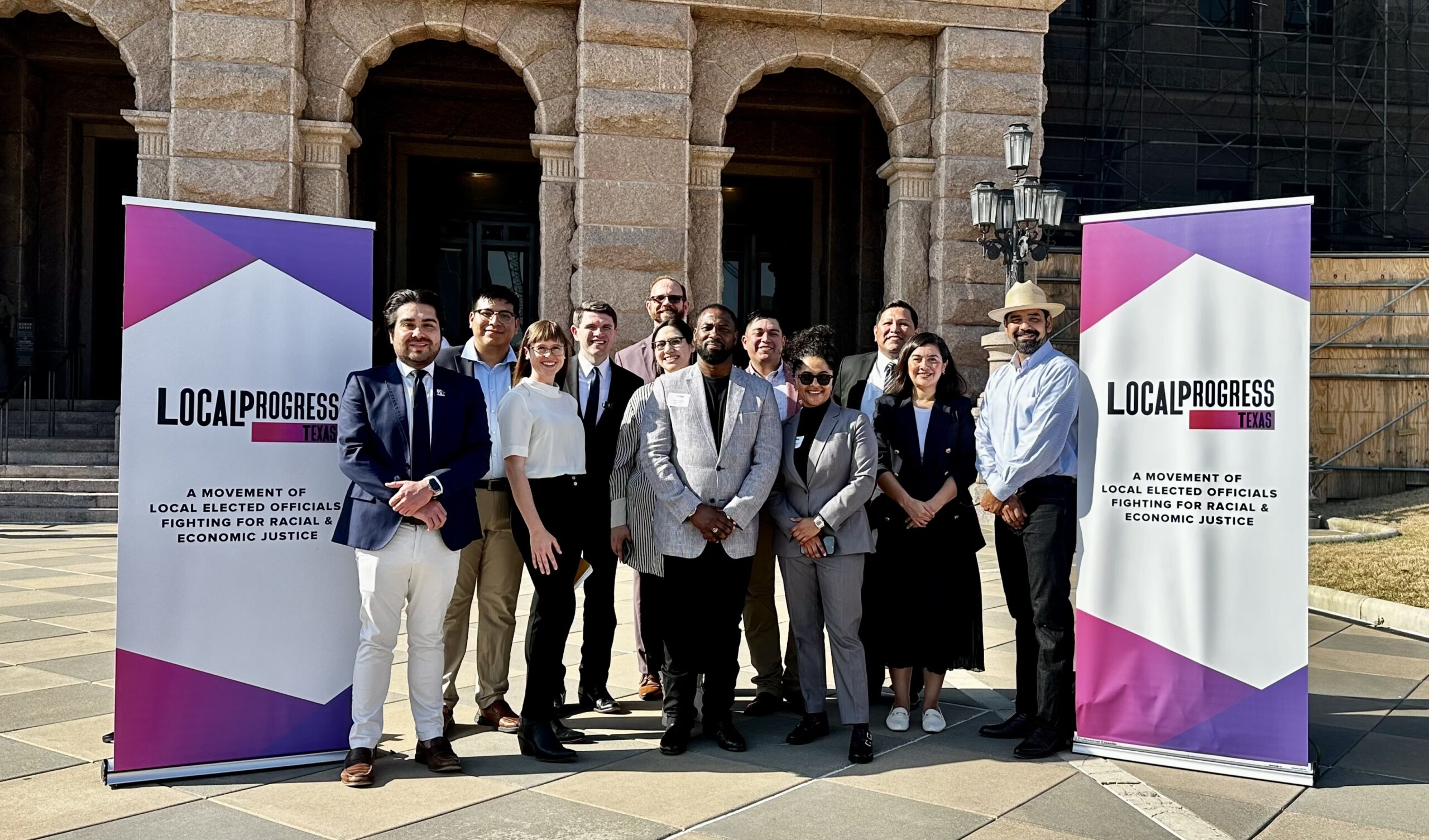 LPTX members and partners posing for a group photo next to two LPTX banners with the state capitol in the background